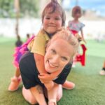 Teacher and preschool child smiling together during outdoor playtime