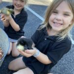 Preschool child smiling while holding a small animal during hands-on learning activity